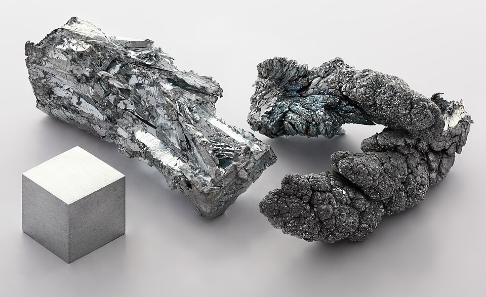 A grey zinc crystal and a small zinc cube